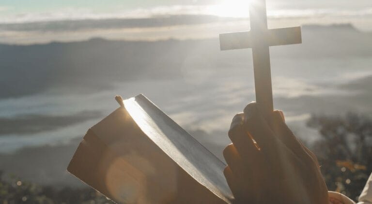 Ilustrasi sebuah tangan yang memegang salib dan Alkitab